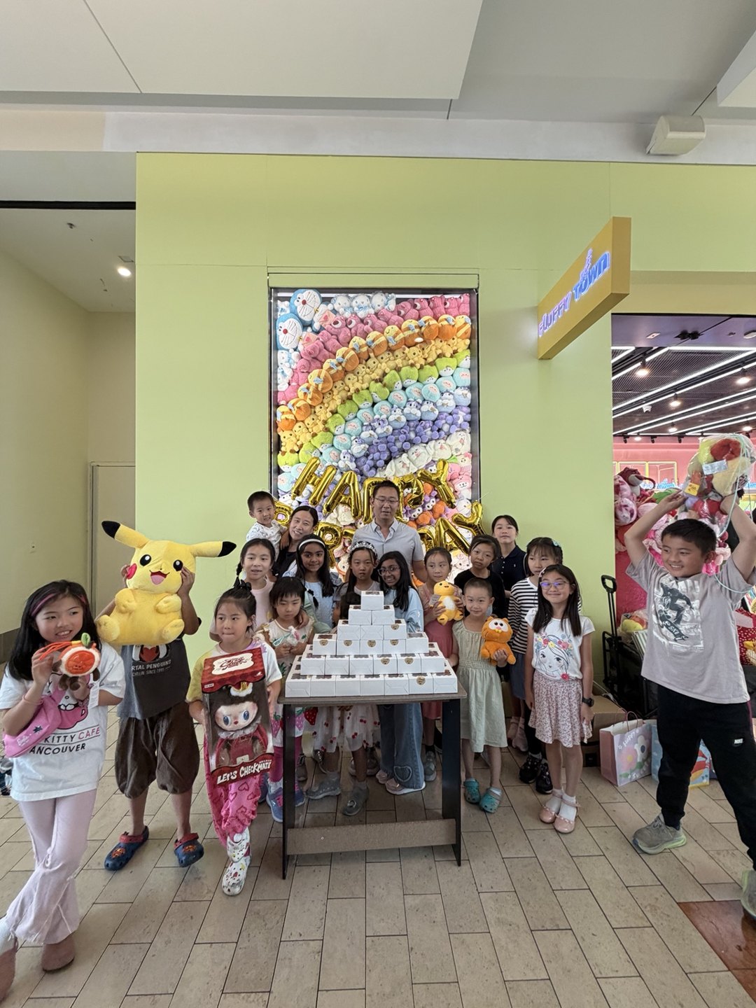 A birthday group gathered around their celebration table, holding plush toys at Fluffy Town